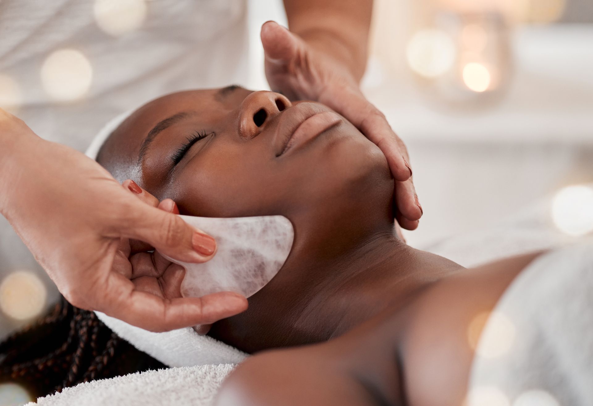 A woman is getting a facial massage at a spa.