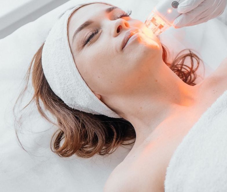 A woman is getting a laser treatment on her face.