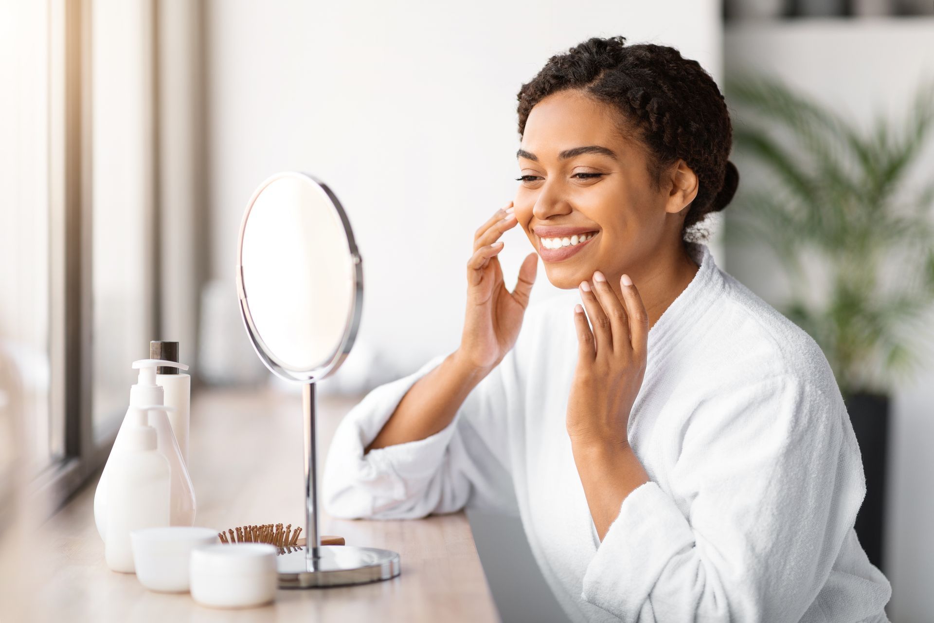 A woman is looking at her face in a mirror.