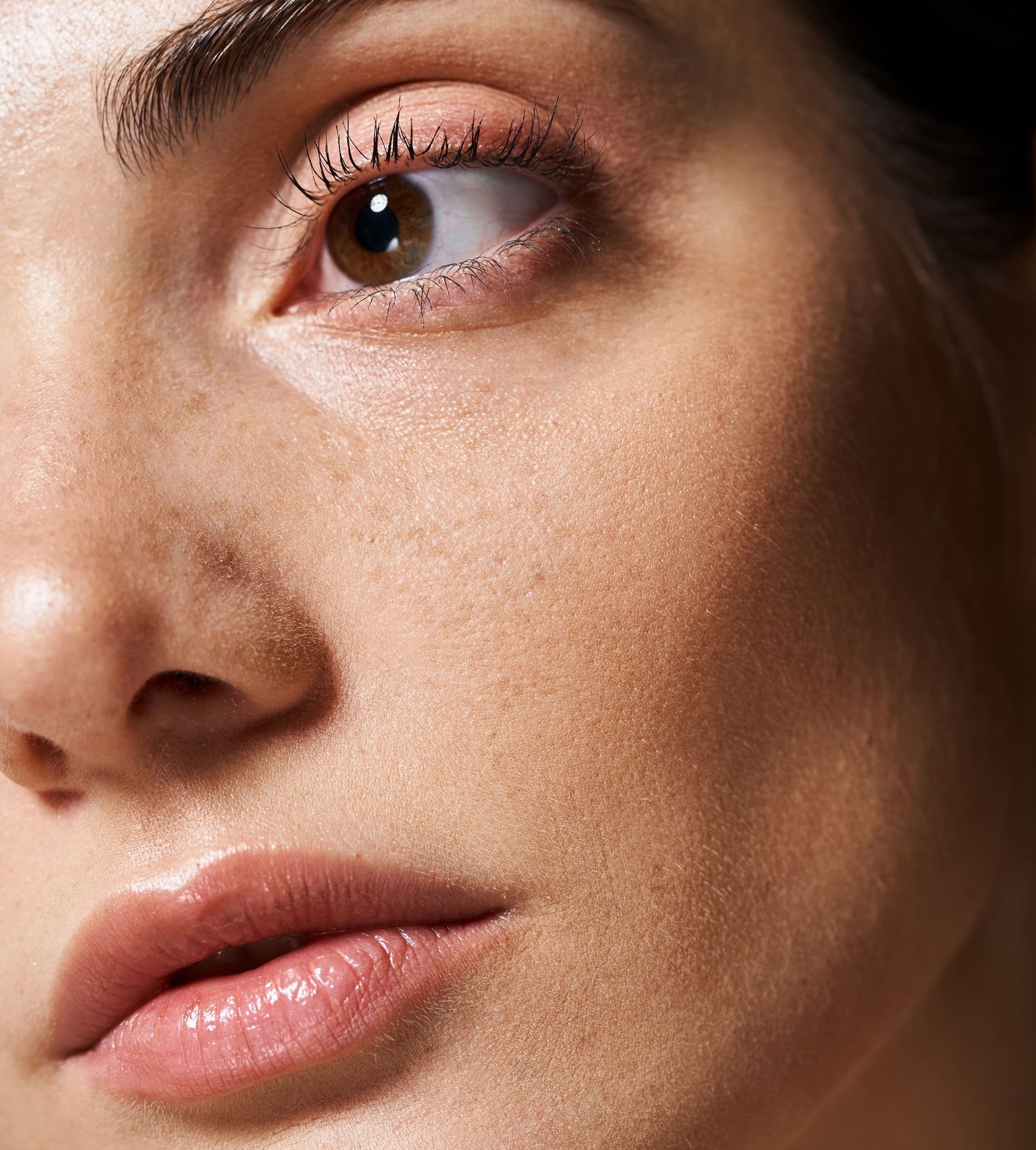A close up of a woman 's face with a brown eye and pink lips.