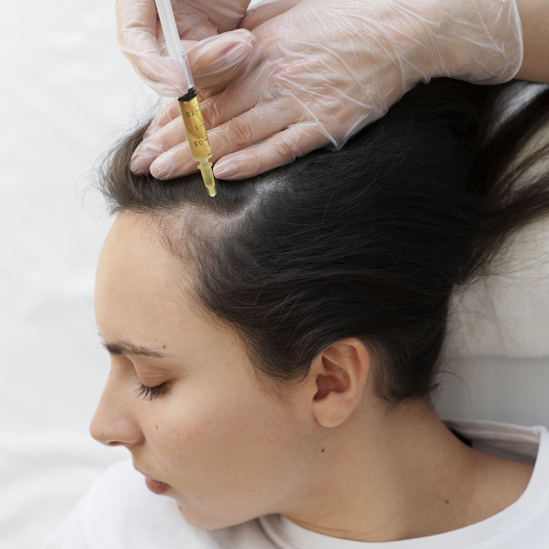 A woman is getting a hair treatment with a syringe