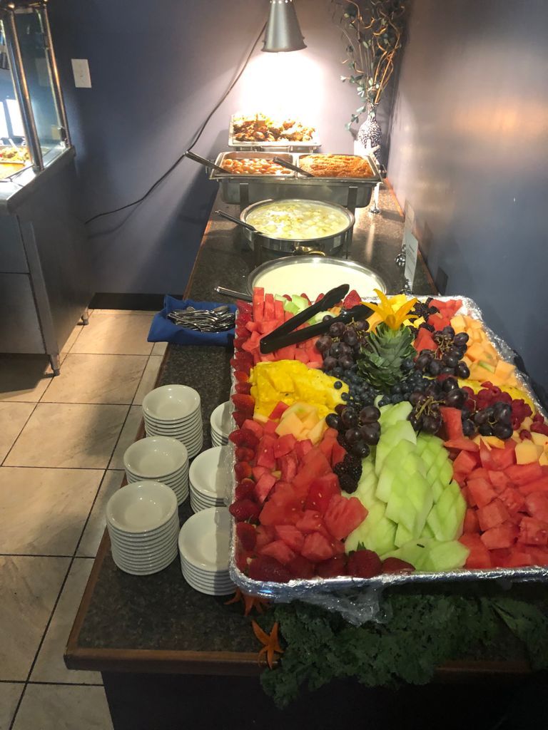 Buffet with a fruit platter, several dishes, and serving bowls.