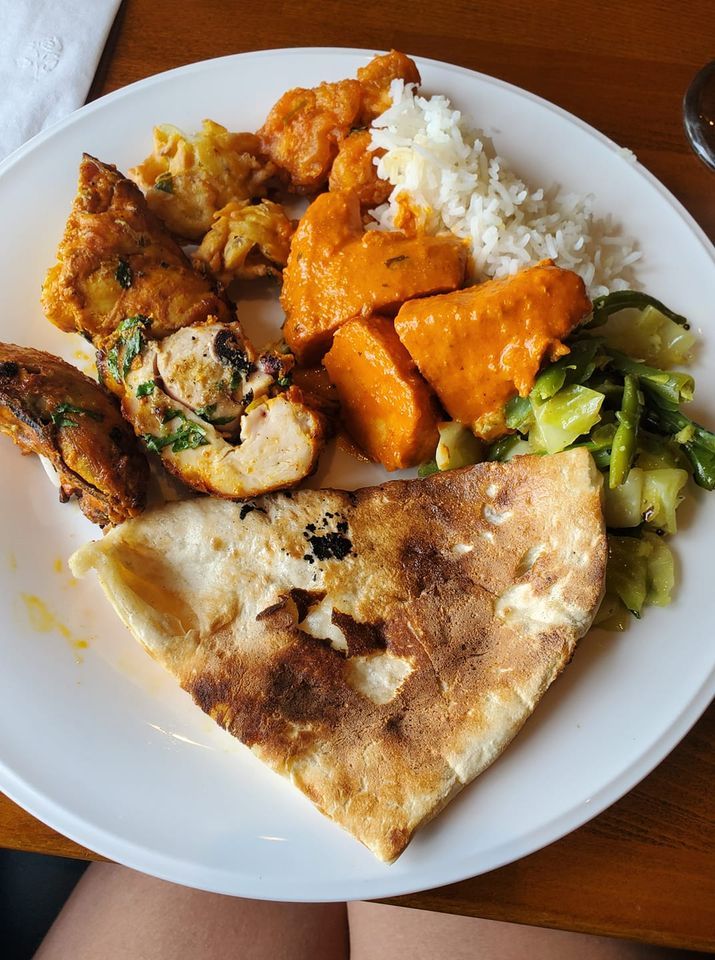 Plate of Indian food: chicken, rice, vegetables, naan, and curry.