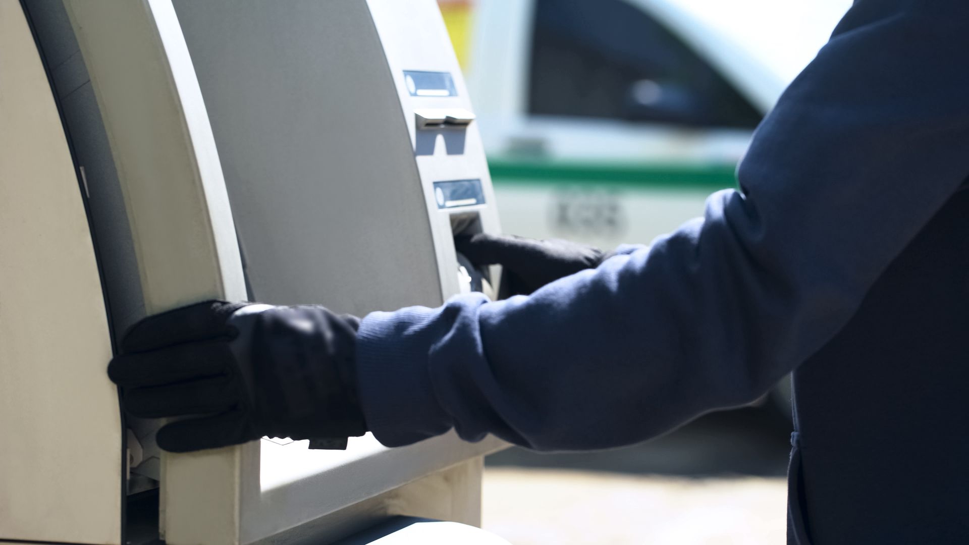 A Person Wearing Black Gloves Using an ATM Outdoors — Clinton Security Services In Mudgee, NSW