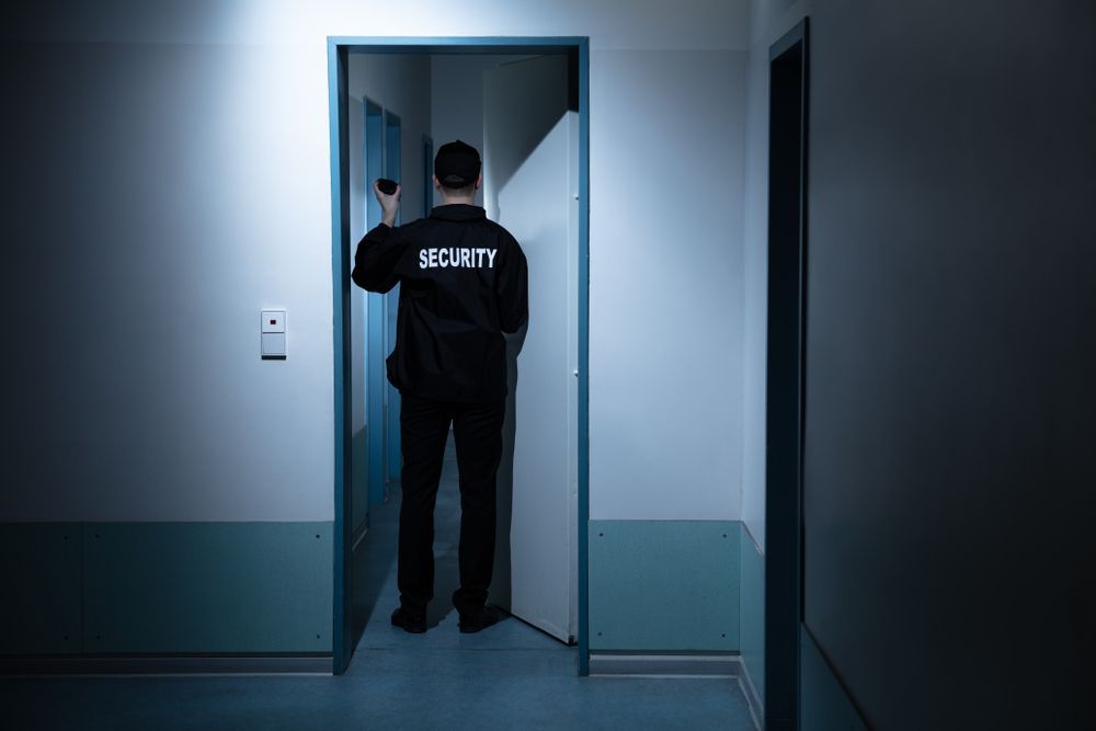 A Security Guard Shining a Flashlight in a Doorway in a Dim Hallway — Clinton Security Services In Goondiwindi, QLD