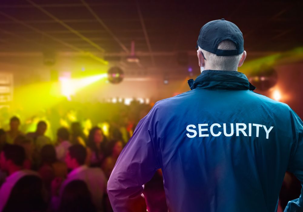 A Security Guard in Blue Uniform Surveying a Crowded, Colourful Nightclub — Clinton Security Services In Warwick, QLD