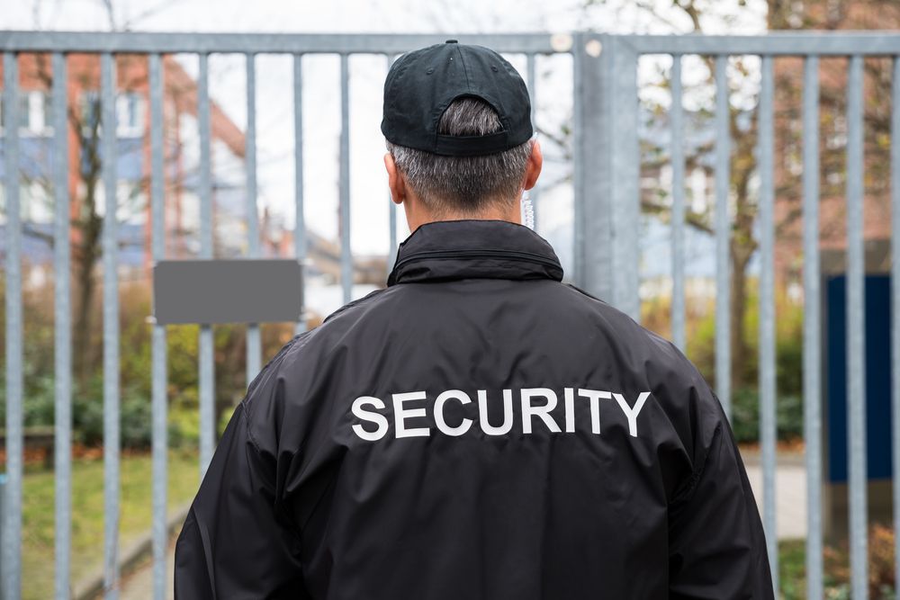 Security Guard Stands in Front of a Gate — Clinton Security Services In Armidale, NSW