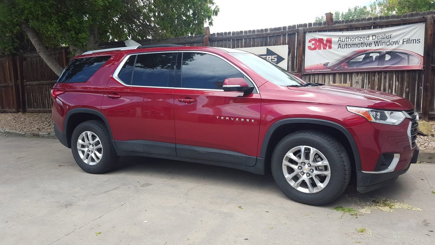 Red SUV parked on a dirt lot near a fence and 3M sign.