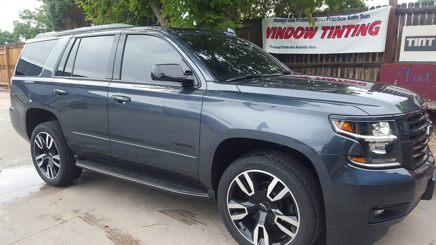 Dark gray SUV parked outside a window tinting shop.