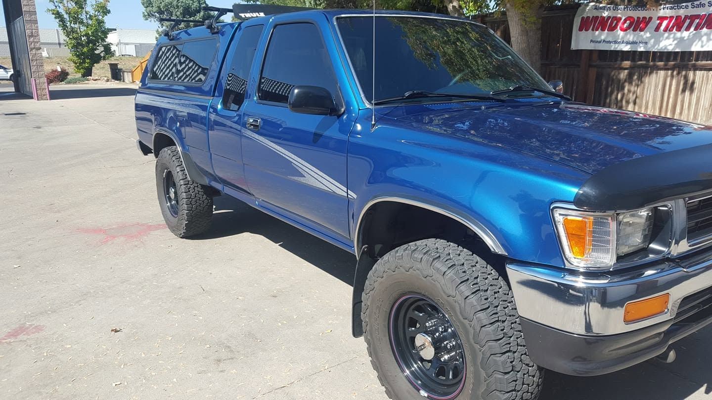 Blue lifted pickup truck parked outdoors in bright sunlight