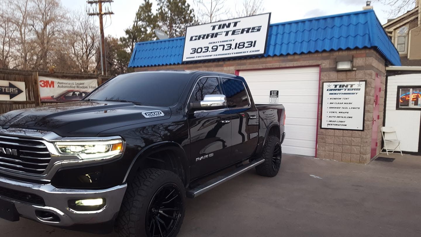 Black pickup truck parked outside a small shop with a blue roof and signage above the entrance