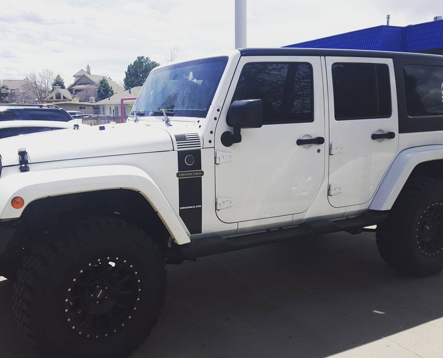 White lifted Jeep Wrangler parked on a snowy street, side view.