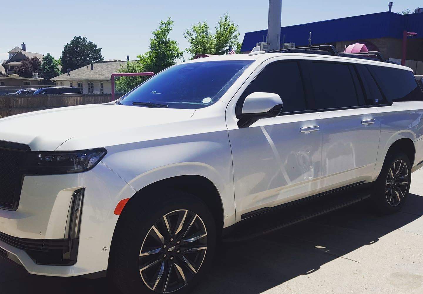 White SUV parked outdoors in bright sunlight, side view with tinted windows and black rims
