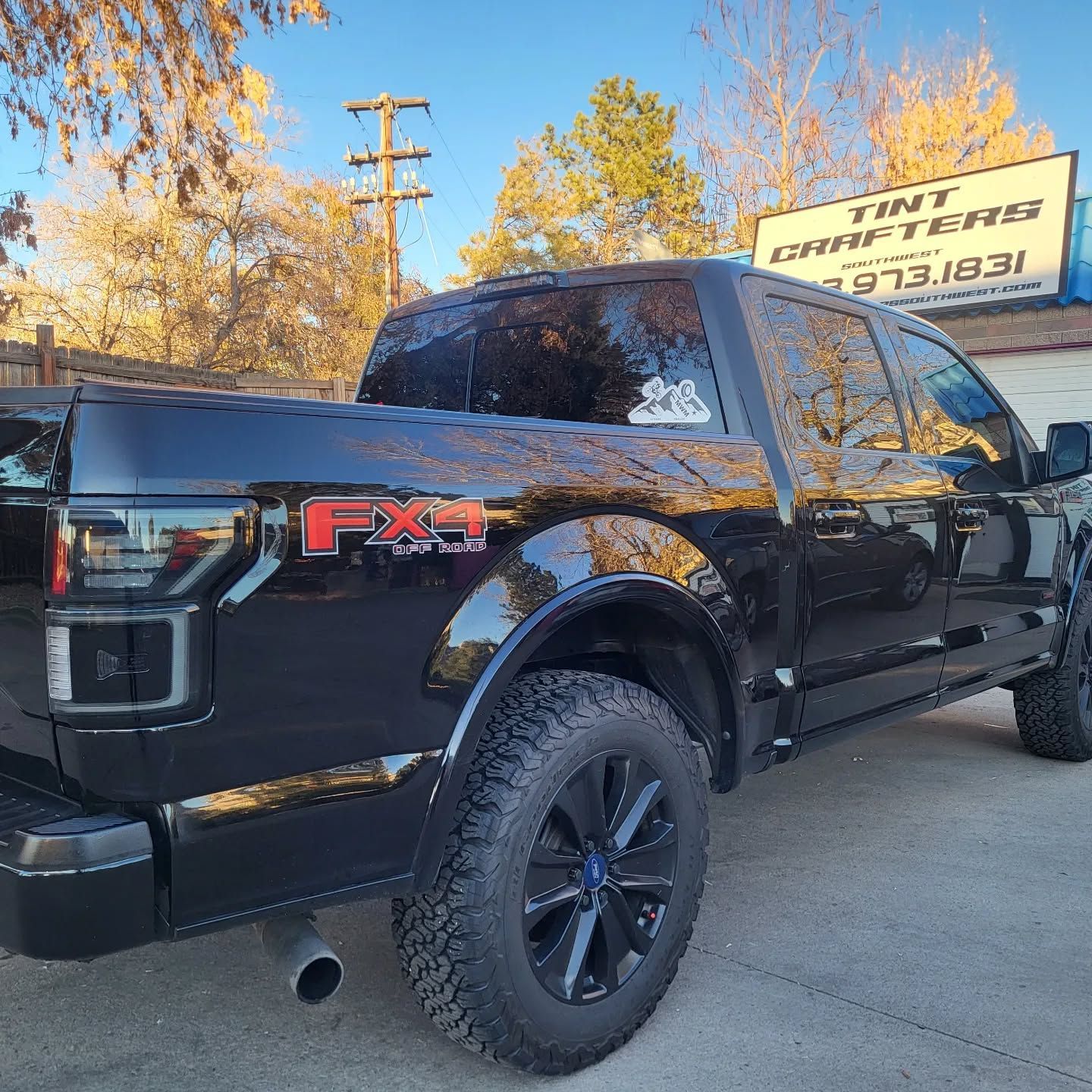 Black Ford F-150 FX4 pickup truck parked outdoors beside a Tint Masters sign.