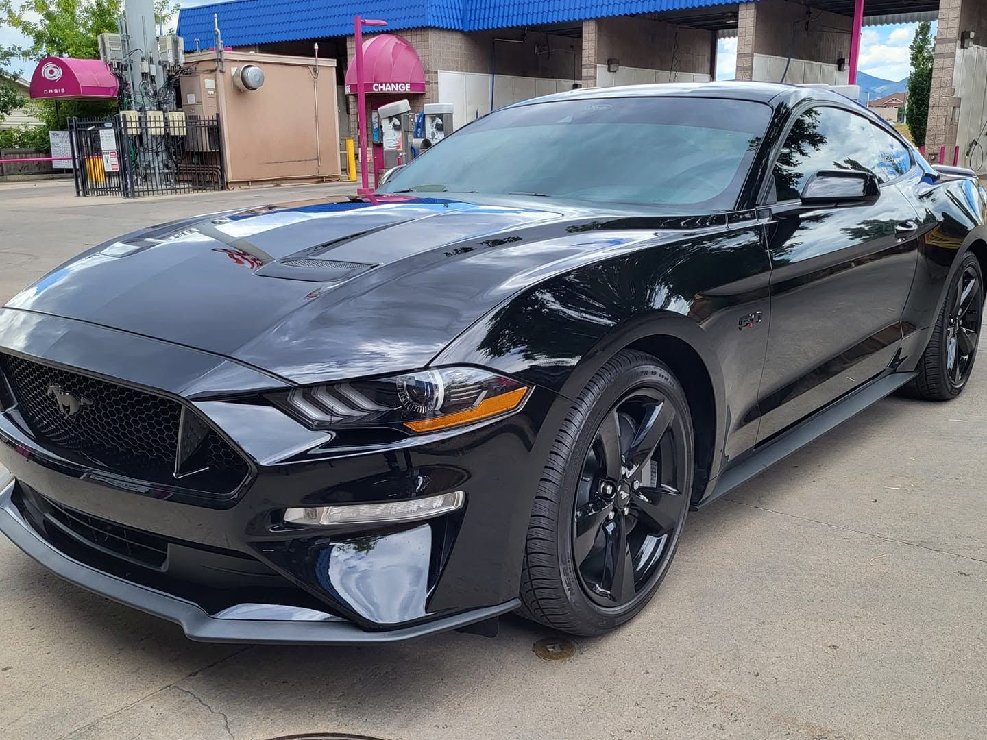 Black sports coupe parked on a street outside a building, front-left view
