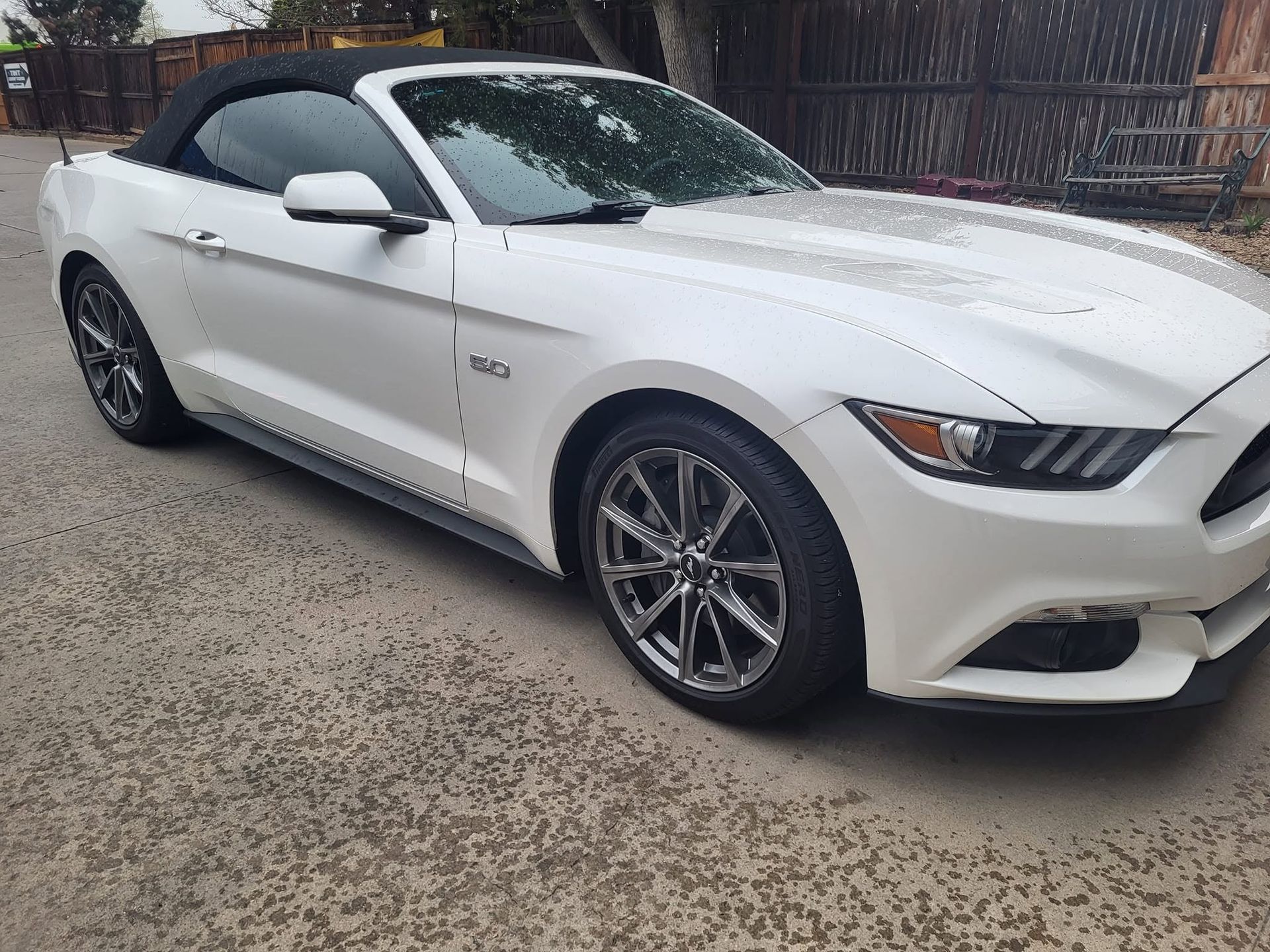 White sports coupe parked on a driveway, front side view with black rims and tinted windows