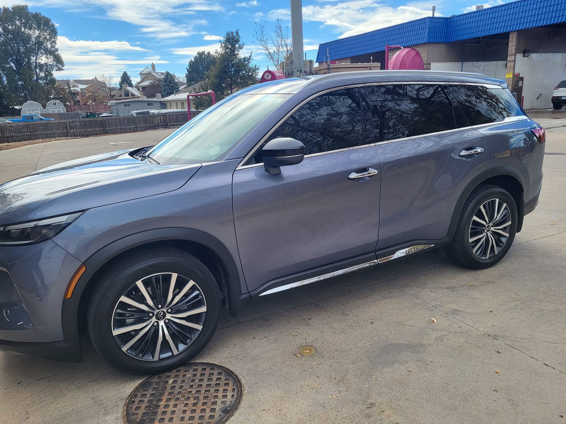 Gray SUV parked outdoors on a sunny street beside a building with a blue roof