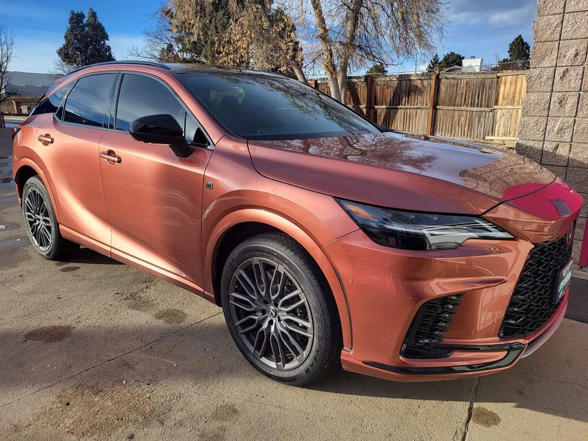 Copper-colored SUV parked outdoors on a sunny street, front three-quarter view.