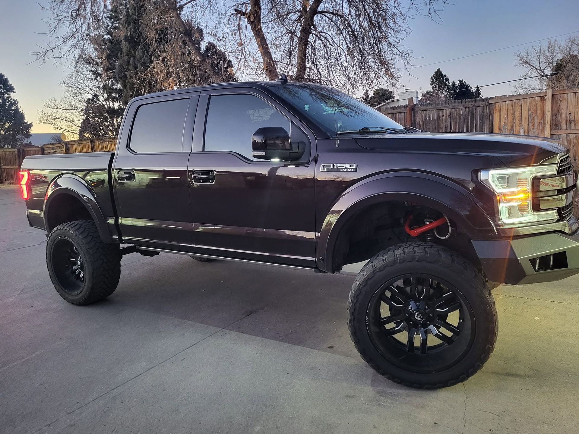 Black lifted pickup truck parked in a driveway at dusk