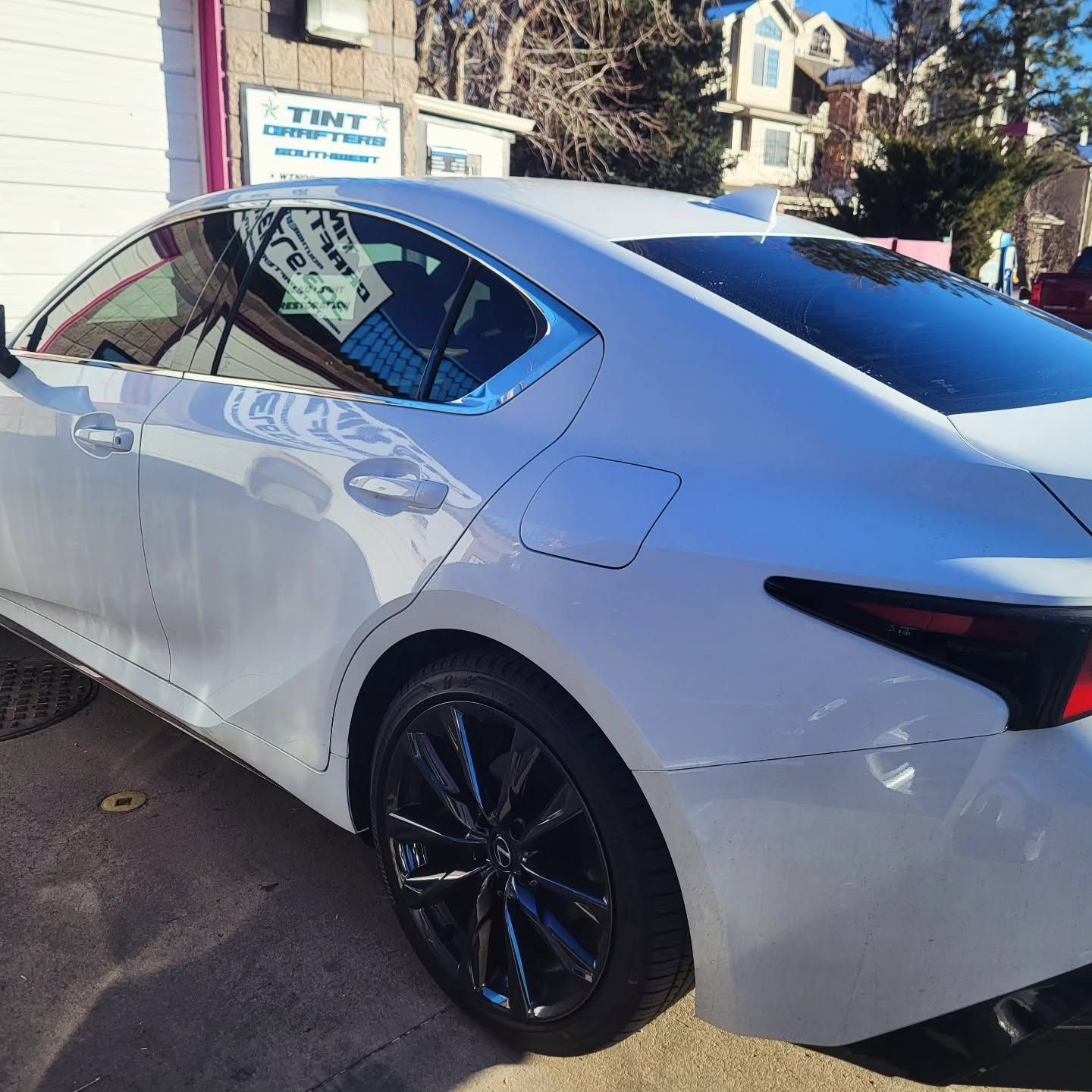 White sedan parked outside a building, side view with black rims in daylight