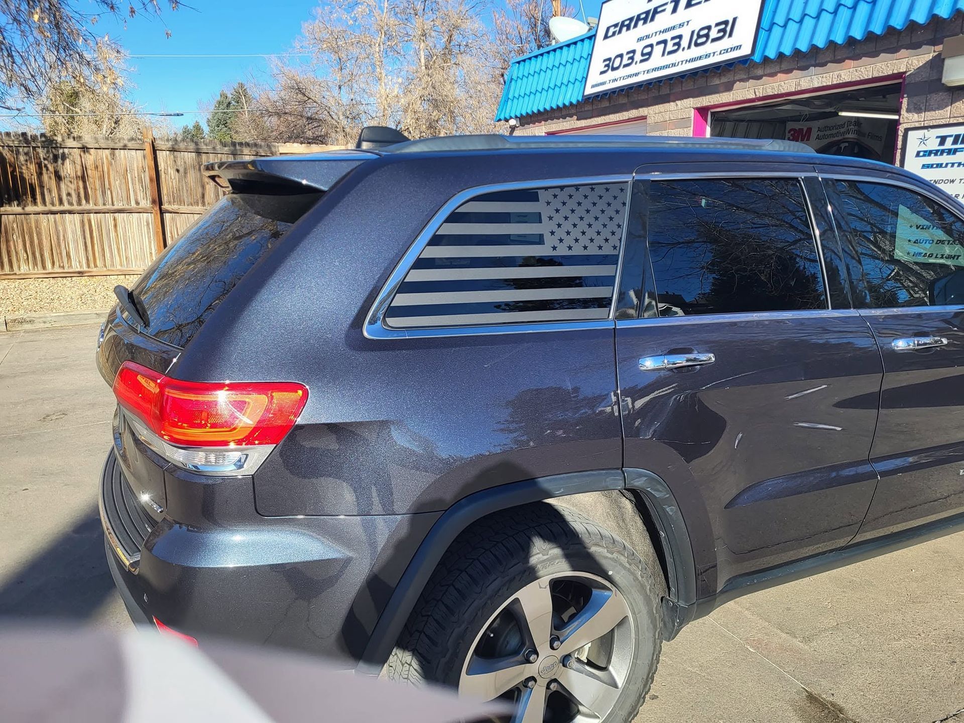 Dark gray SUV parked outside a building with a blue roof on a sunny day