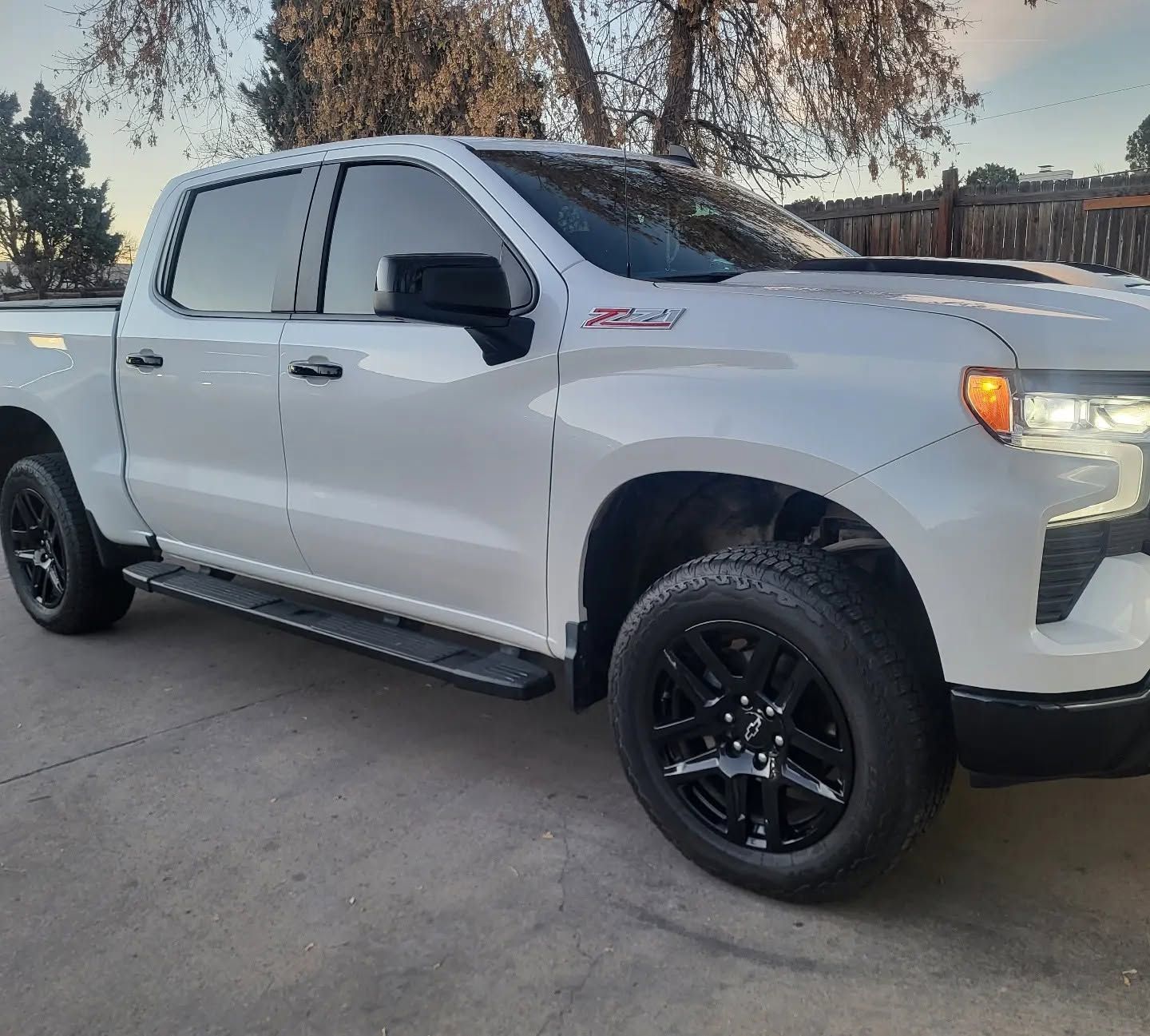 White pickup truck with black wheels parked in a driveway at dusk