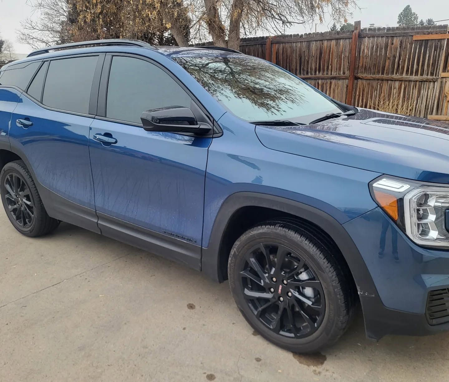 Blue SUV parked in a driveway, side view with black wheels and tinted windows.