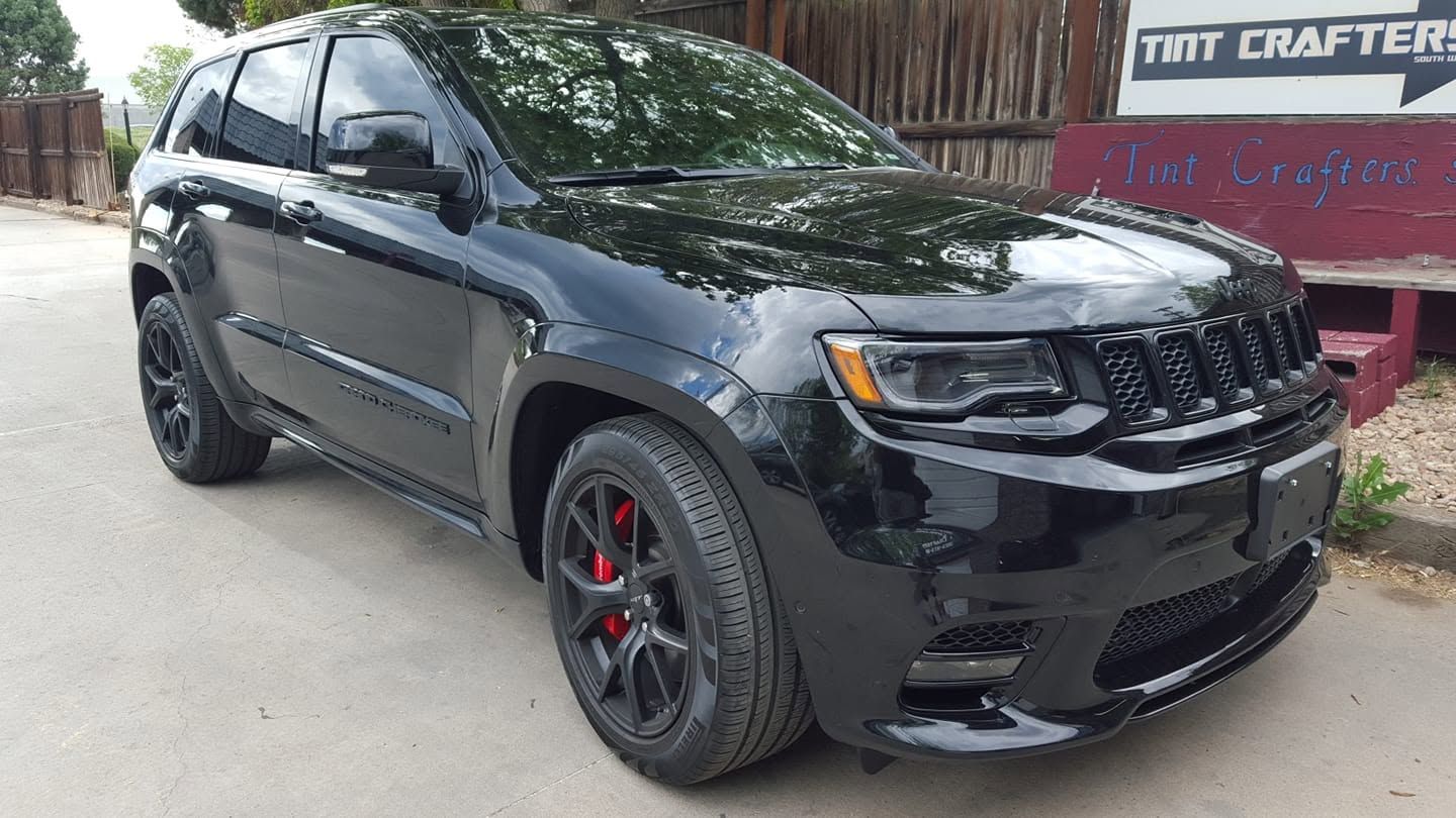 Black Jeep Grand Cherokee parked outdoors with red brake calipers and tinted windows