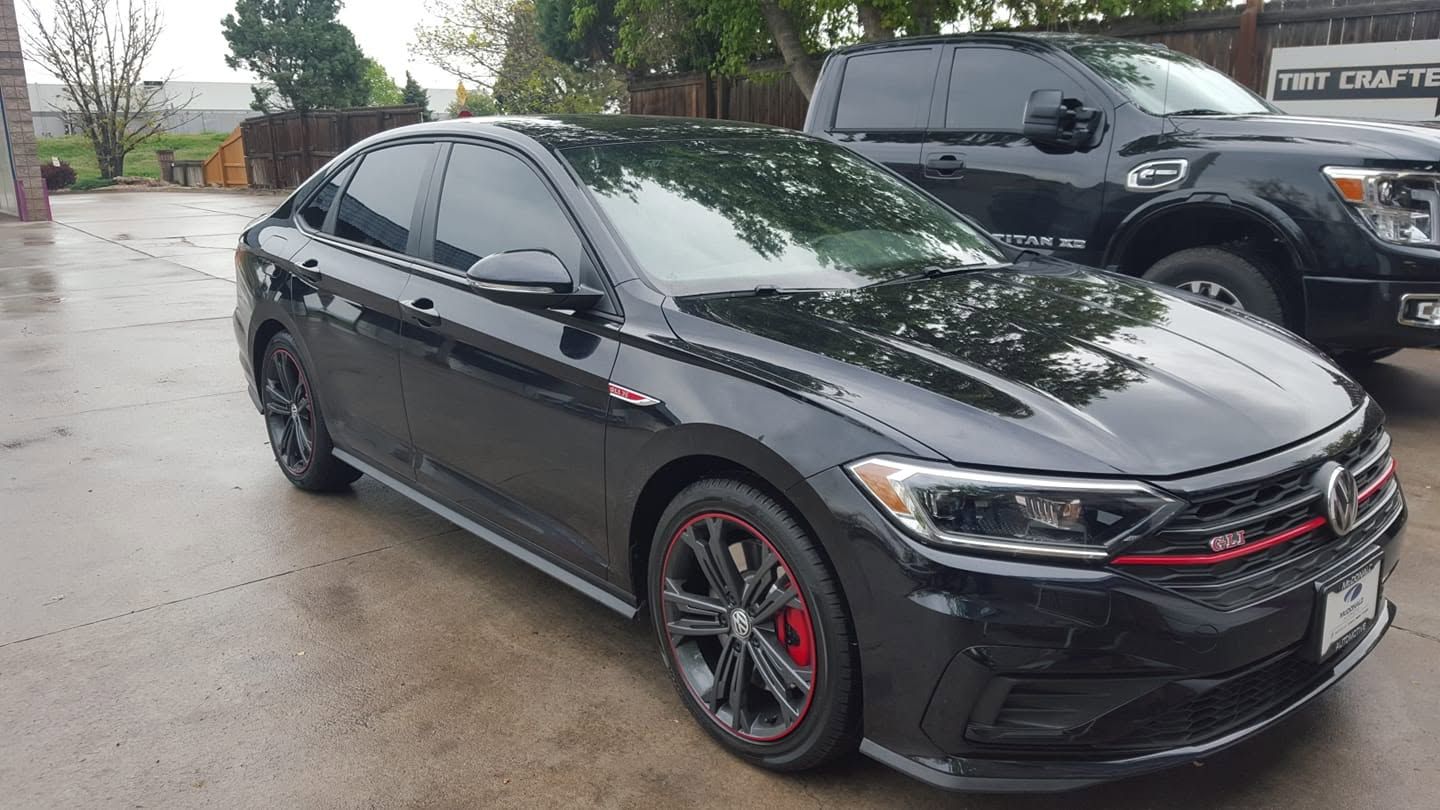 Black sedan parked on a wet lot, with red accents and a black SUV beside it.