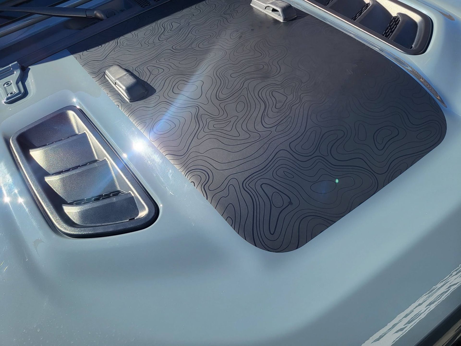 Car dashboard close-up with textured black center console, buttons, and silver trim under blue light