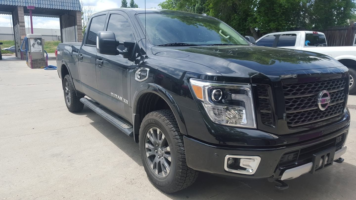 Black Nissan pickup truck parked outdoors near a building on a sunny day