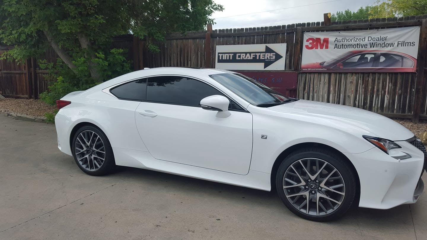 White coupe parked outside a 3M shop, side view on a street