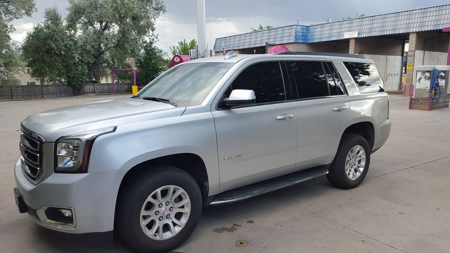 Silver SUV parked on a roadside near a low building and trees