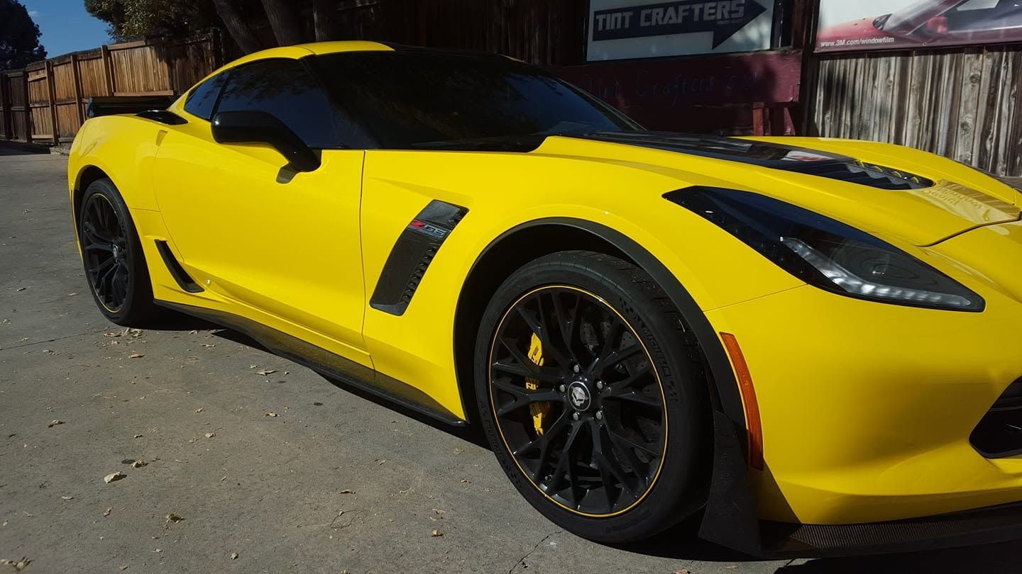 Yellow sports car parked outdoors on a street, viewed from the front side.