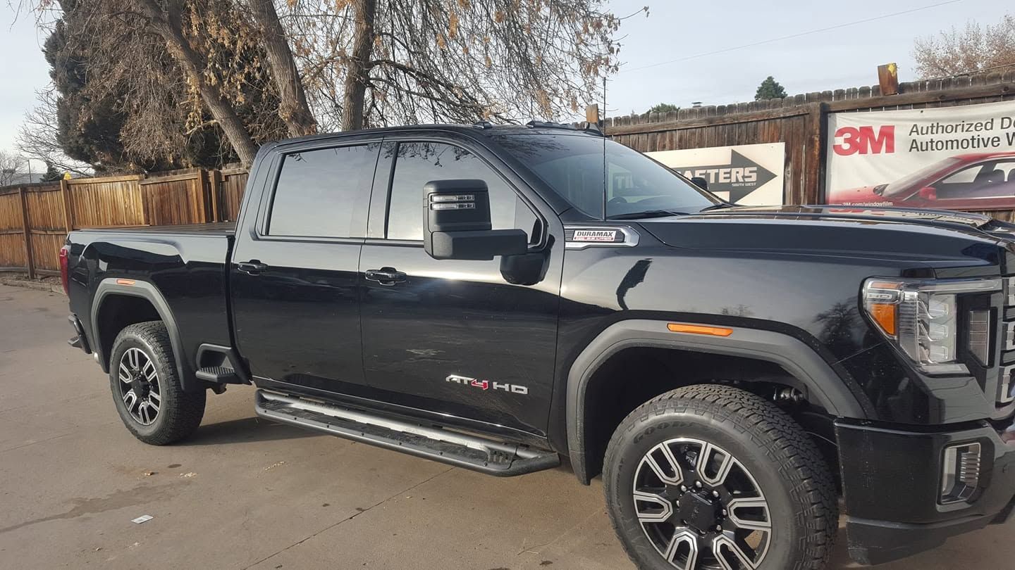 Black pickup truck parked outdoors beside a building, side view