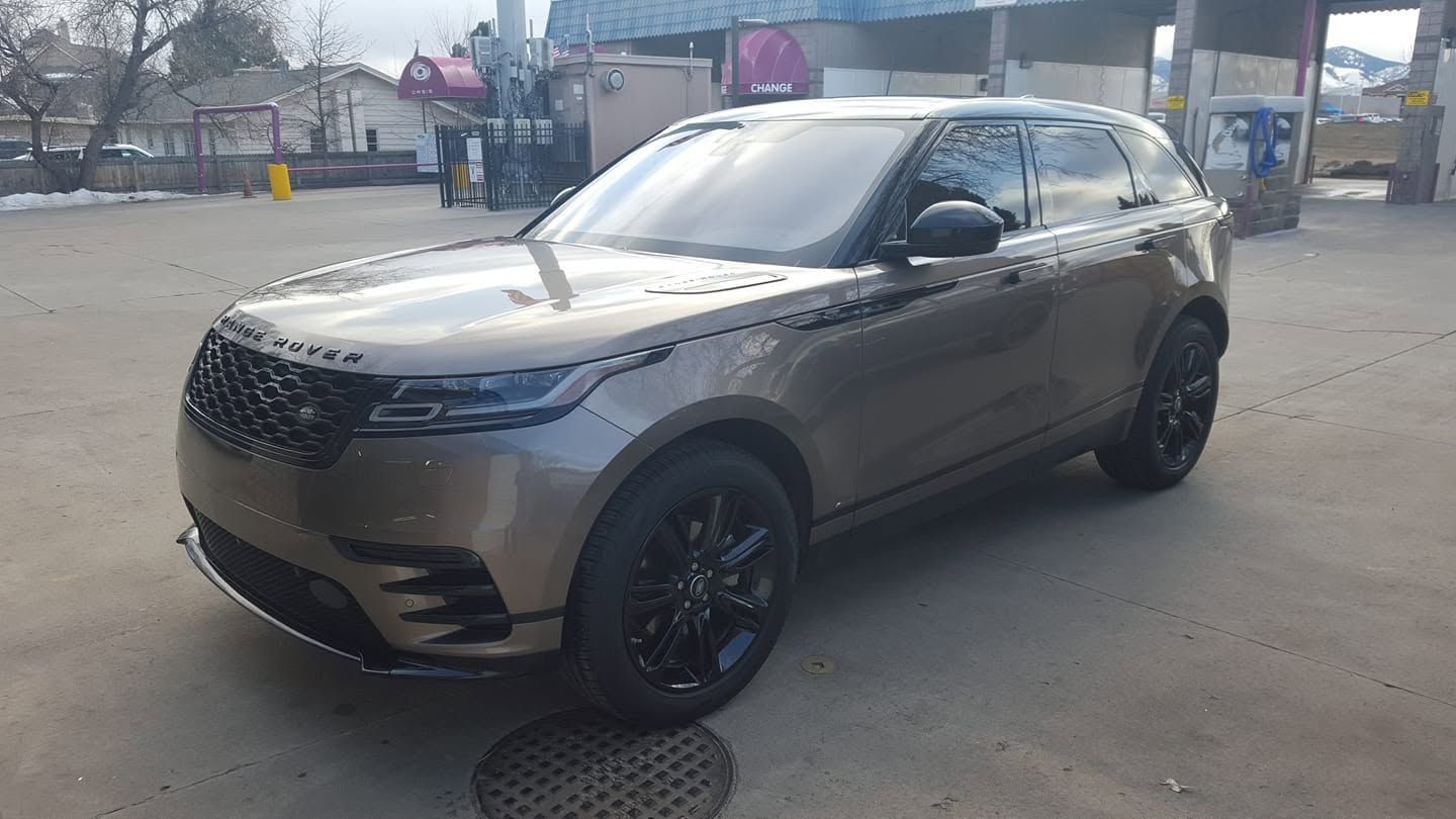 Gray SUV parked outdoors on a street near a gas station, front-left view.
