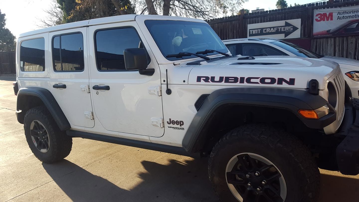 White Jeep Rubicon off-road SUV parked outdoors in sunlight, side view with black wheels