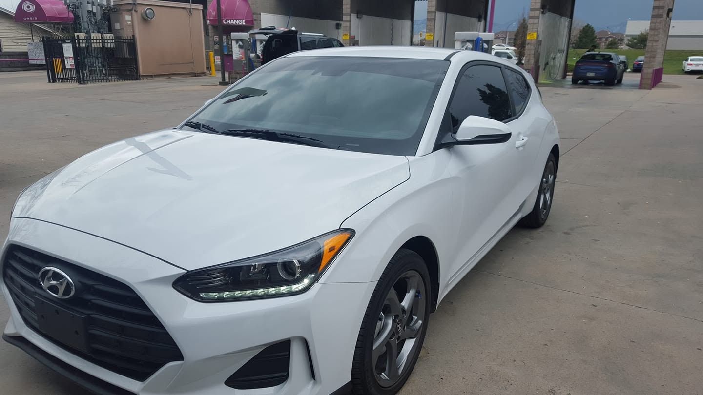 White Hyundai sedan parked outdoors in a lot, front-left view.