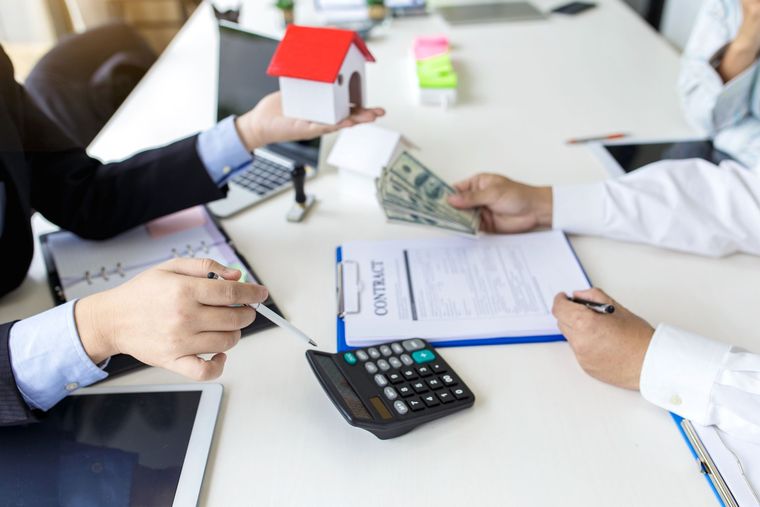 Business meeting reviewing house contract and cash with calculator on office desk