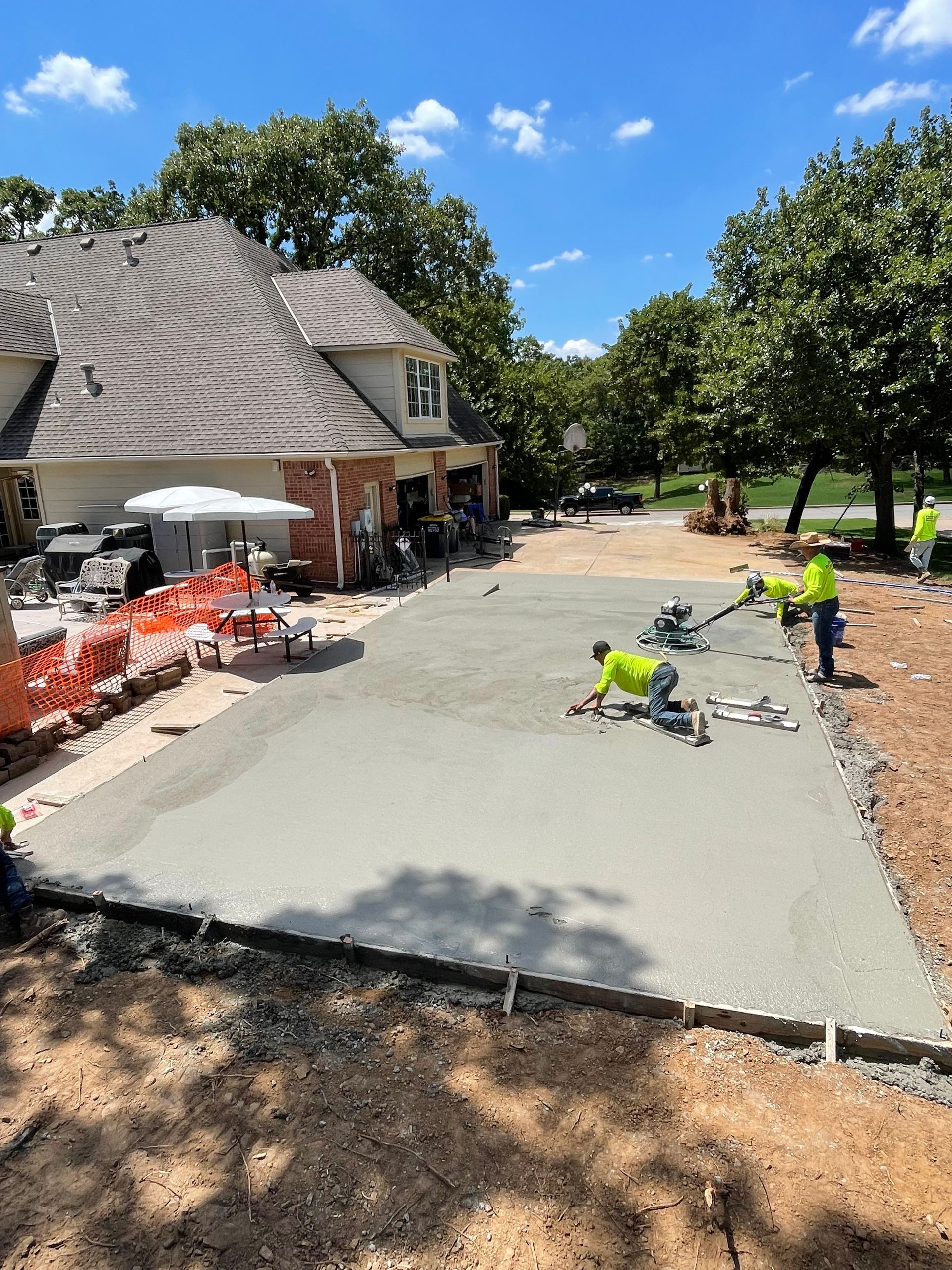 Concrete sidewalk with dark stain, next to brick pavers and dry grass.