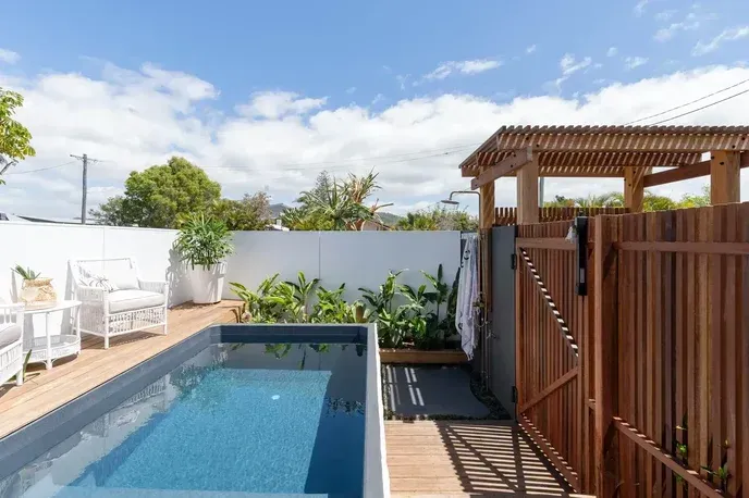 Concrete pool with steps next to a covered building, set on dirt.