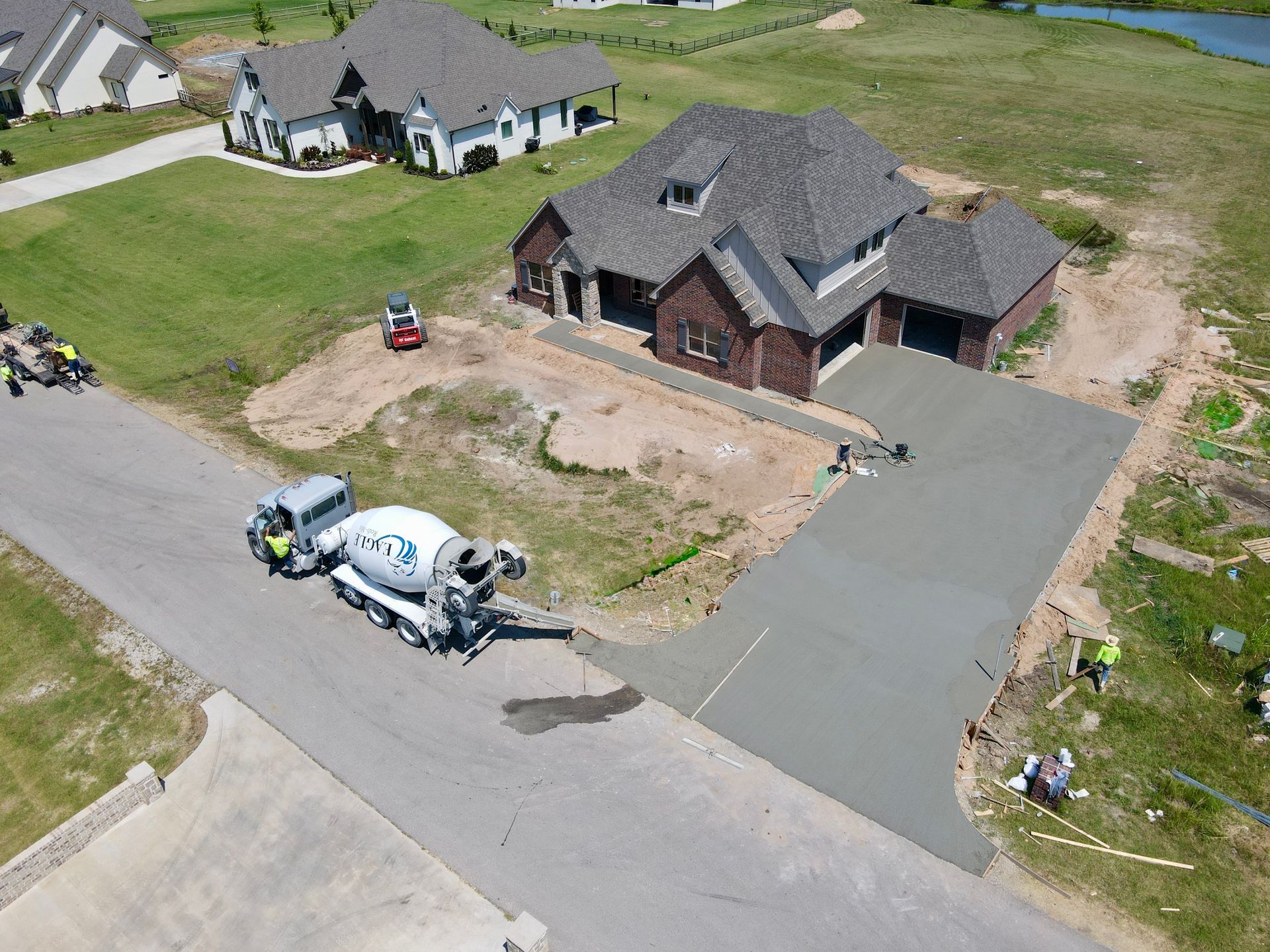 Concrete sidewalk with dark stain, next to brick pavers and dry grass.