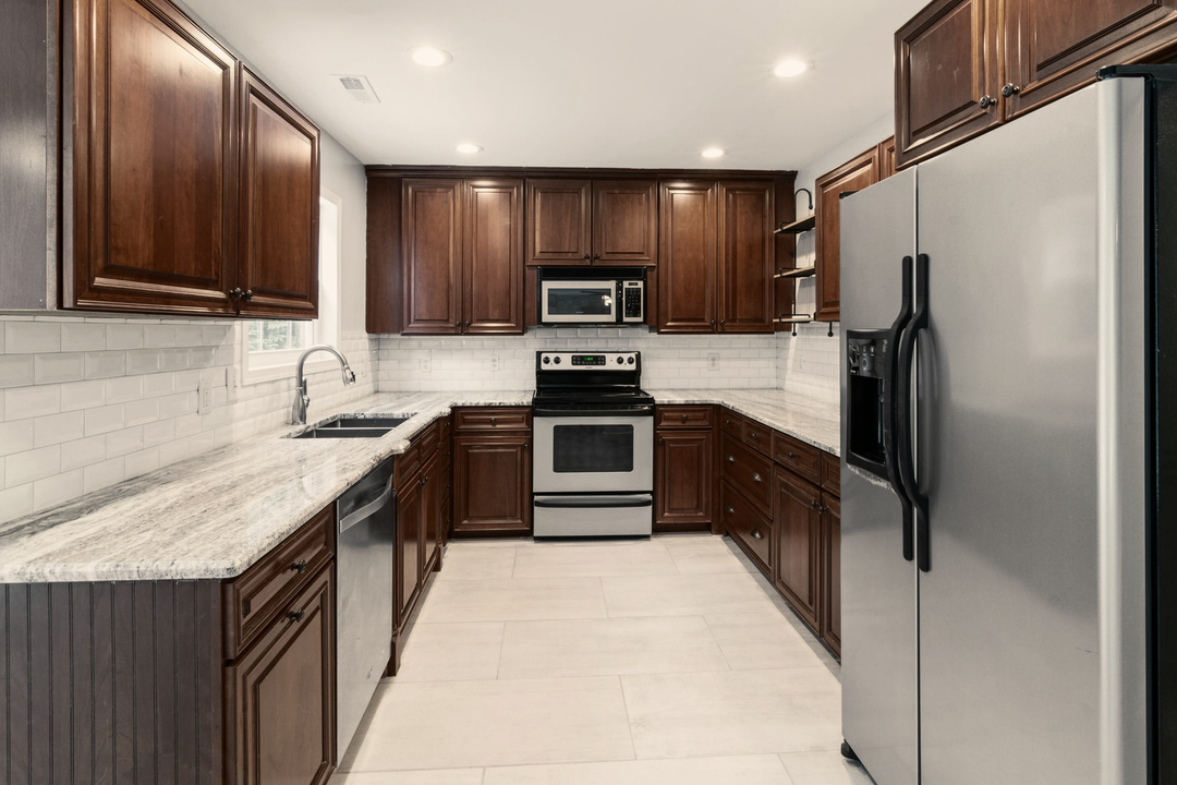 U-shaped kitchen with dark brown cabinets, stainless steel appliances, and white countertops.