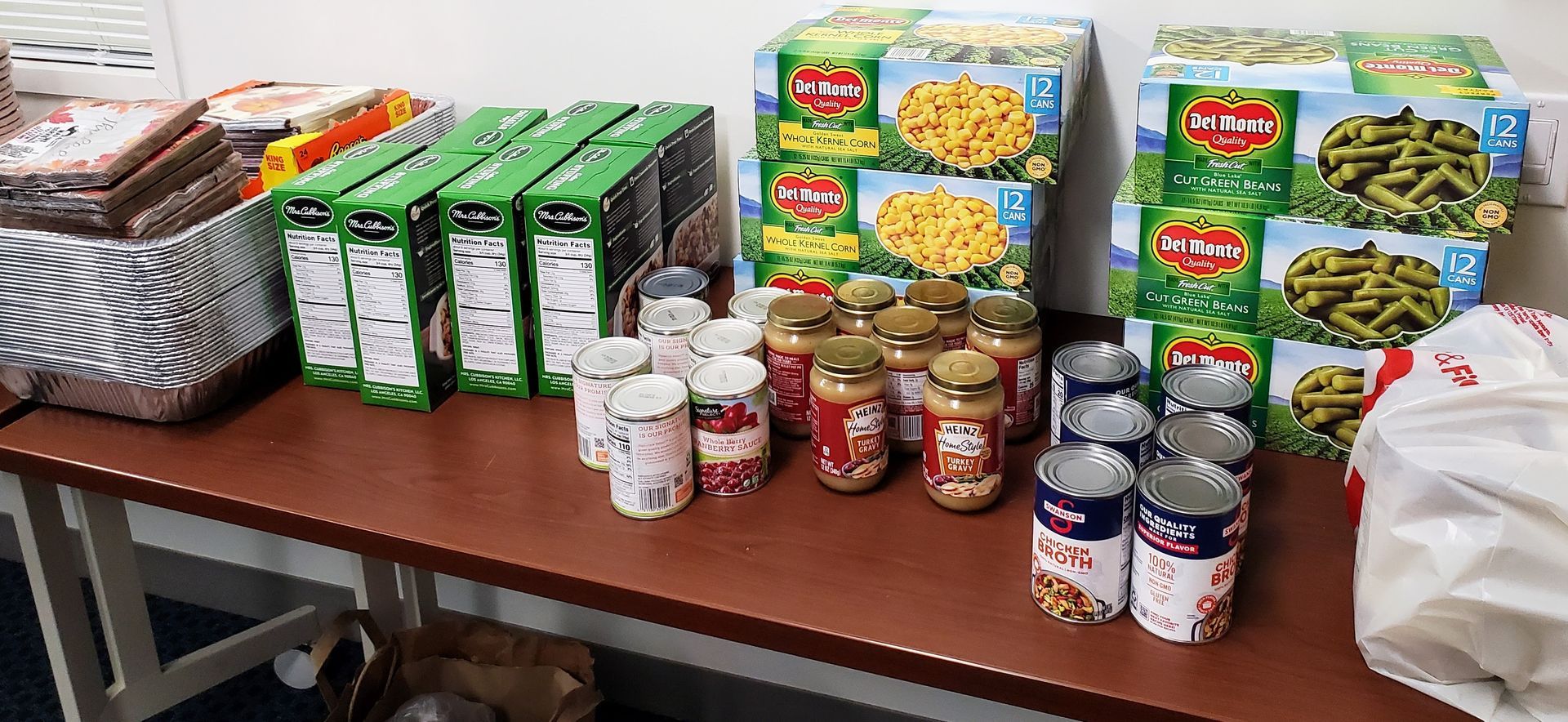 A table filled with various non-perishable food items including boxes of macaroni, green beans, and jars of peanut butter.