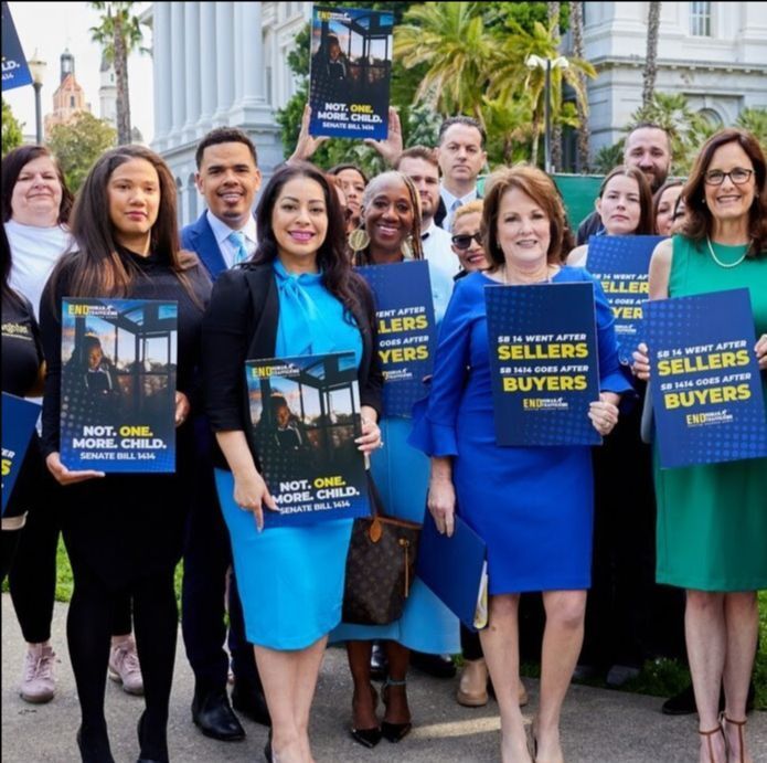 A group of people standing outdoors holding signs that say 