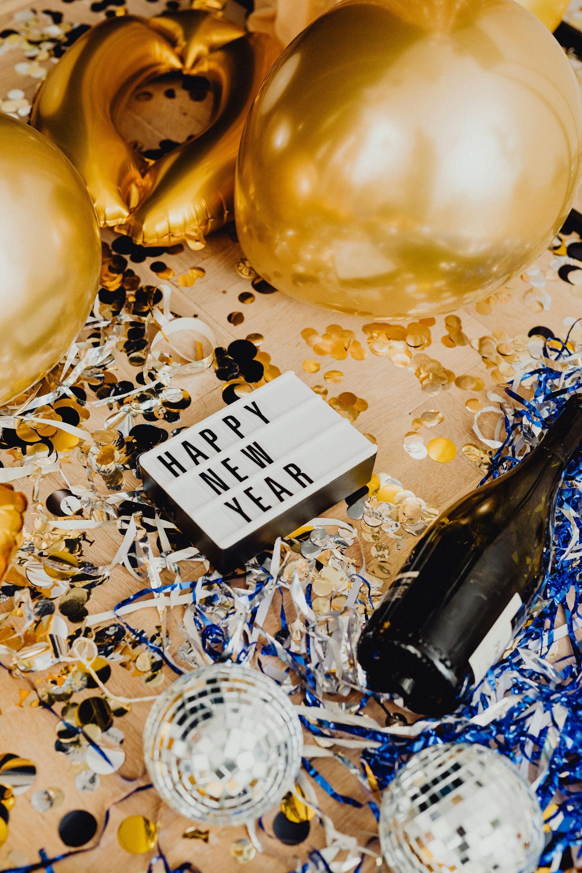 A New Year's party scene with gold balloons, confetti, a