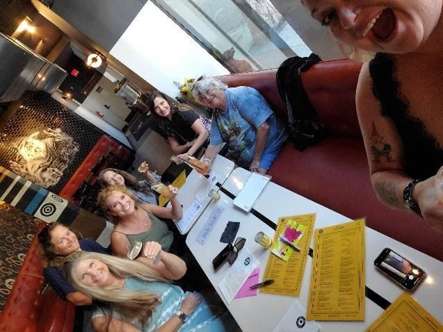 A group of people sitting in a red booth at a restaurant, looking toward the camera during a meal.