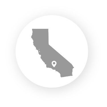 A grey silhouette of California centered on a white circle, with a location pin marker in the southern region.