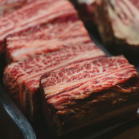 Close-up of marbled raw beef cuts on a dark tray