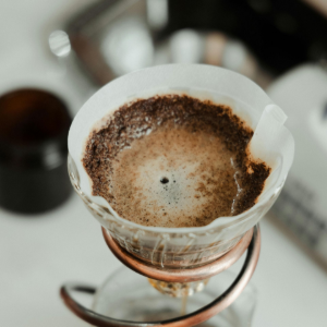 Coffee drips through a paper filter into a glass pour-over dripper on a stand